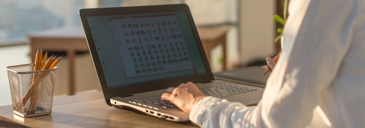 A person working at a desk on a laptop, focusing on organizing digital files in a bright workspace.